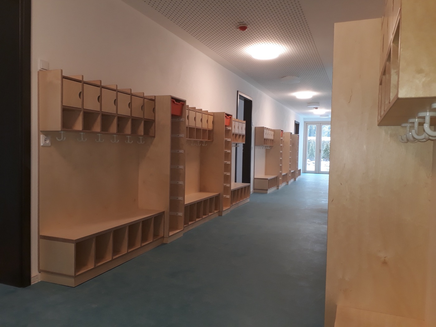 Garderobeneinbauten aus Holz mit Sitzbänken, Haken und Fächern